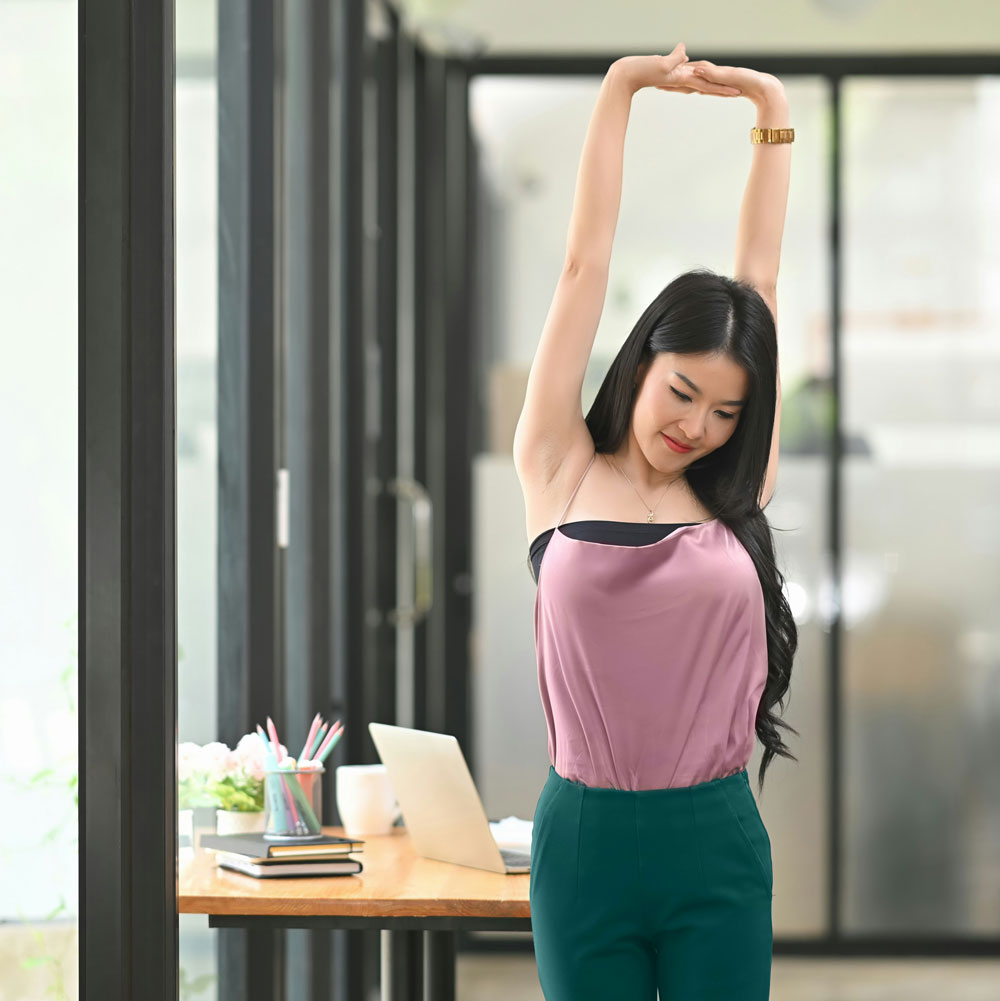 Woman standing to stretch near her desk