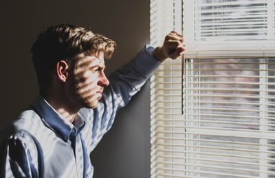 Man staring out of a window looking thoughtful 