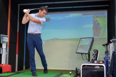 man swinging at golf simulator
