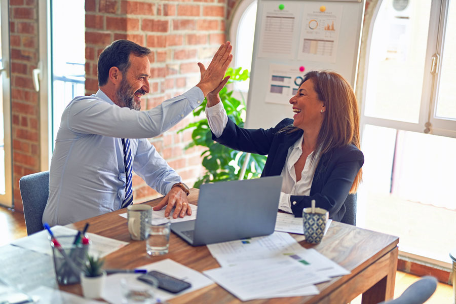 man and woman high-fiving at work