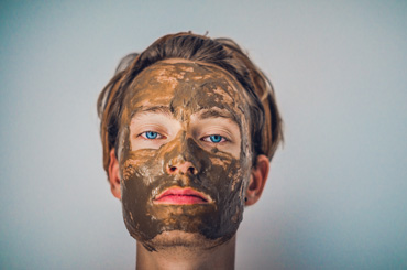 spa treatments woman with mud pack on face