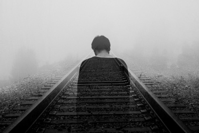 Ghostly image of a depressed man on a rail track